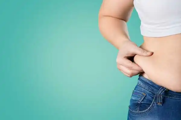 Image of woman pinching her love handles to show weight gain Beaconsfield